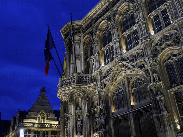 Monumental historic building with detailed facades and flags against a dramatic evening sky, Ghent, Belgium, Europe