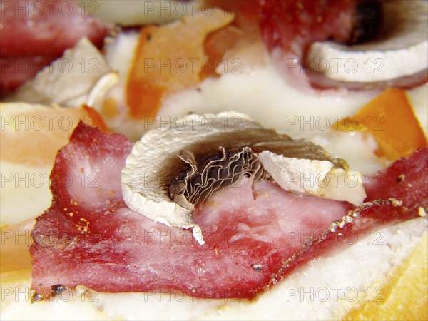 Sliced champignon on top of piece of ham and melted cheese
