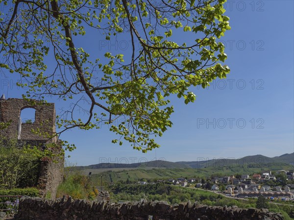 Viewpoint with ruins and leaves in the foreground, view of cityscape under blue sky, saarburg, germany