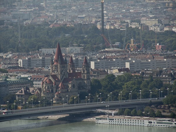 Historic church with striking towers in the middle of a dense urban landscape and a bridge over the river, Vienna, Austria, Europe
