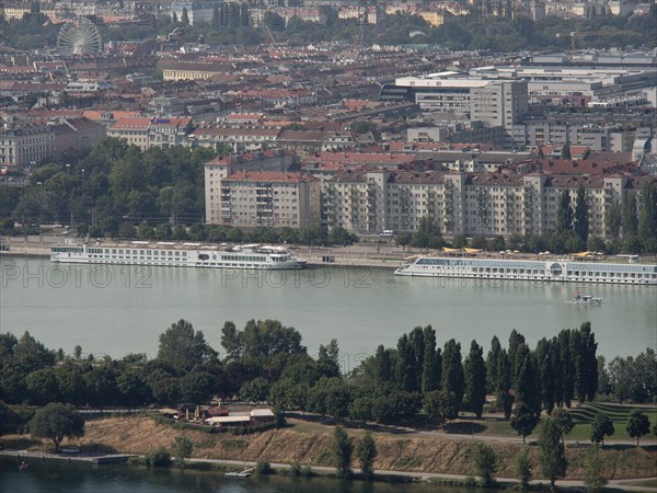 Panorama of a city by the river, lined with trees and large residential buildings in the background, Vienna, Austria, Europe