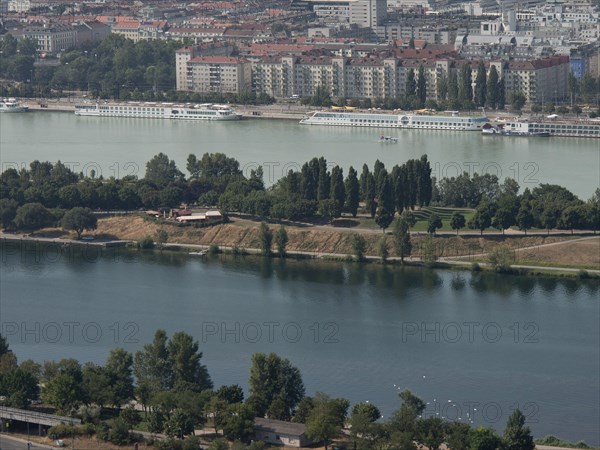 View of a riverside town with park-like areas, trees and residential buildings in the background, Vienna, Austria, Europe