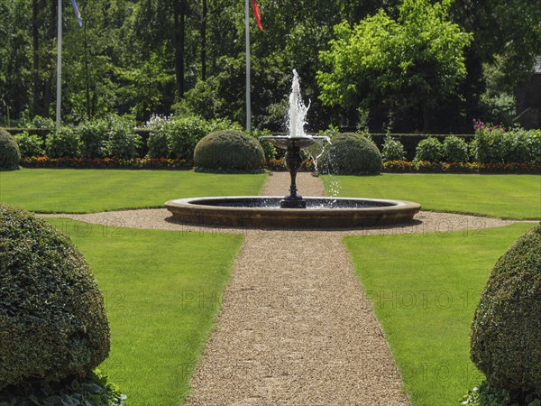 A well-tended garden with a bubbling fountain in the centre on a summer's day, ochtrup, münsterland, germany