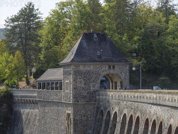 A dam with a historic stone building, surrounded by forest and trees, with a road and bridge lamps, Waldeck, Hesse, Germany, Europe