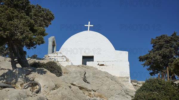 White church with a cross on a rocky hill surrounded by trees under a clear blue sky, Chapel of Agios Panteleimon, Kastro Monolithou, Monolithos Castle, rock castle, Monolithos village, Rhodes, Dodecanese, Greek Islands, Greece, Europe