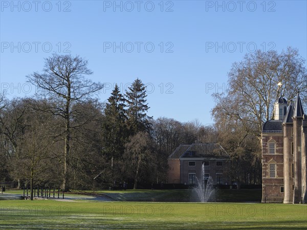 Historic castle with a fountain in the foreground in a well-kept park on a sunny day, ruurlo, gelderland, the netherlands