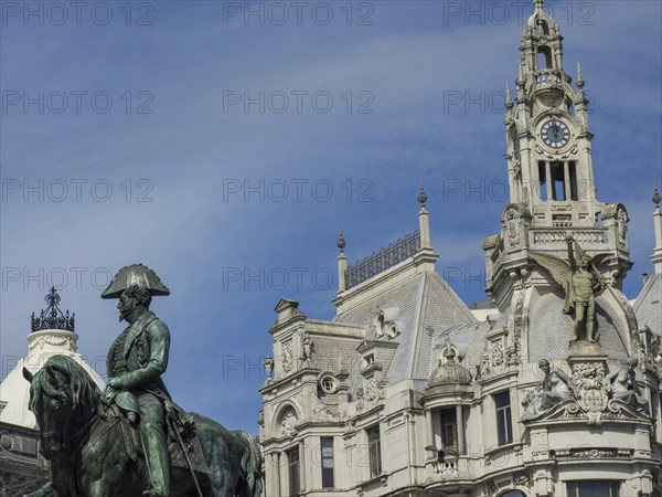 Equestrian statue in front of an ornate clock tower and historic buildings under a slightly cloudy sky, Porto, Douro, Portugal, Europe