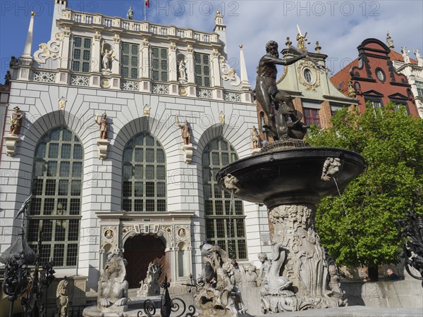 Row of Renaissance buildings next to a large decorative fountain with figures and sculptures, Gdansk, Poland, Europe