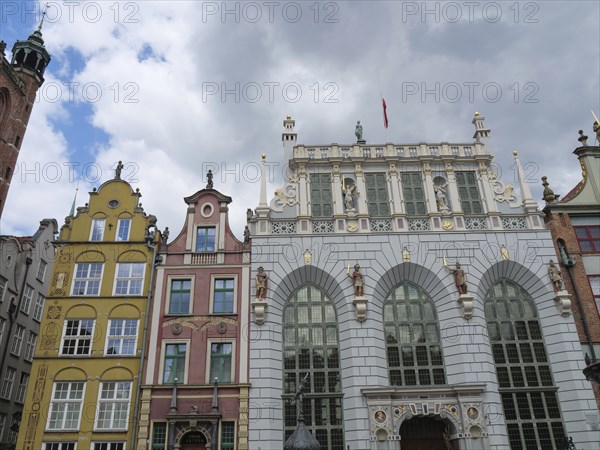Several historic buildings with colourful, decorated facades under a cloudy sky, Gdansk, Poland, Europe