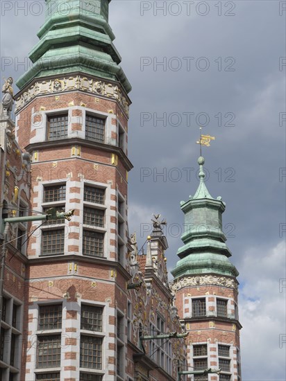 Historic buildings with distinctive towers and decorations under a cloudy sky, Gdansk, Poland, Europe