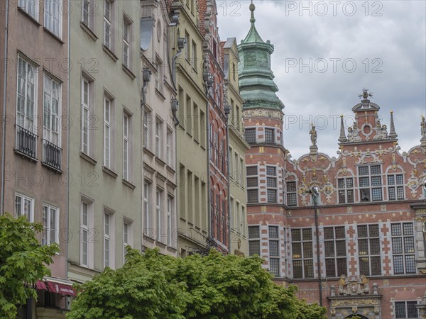 Historic buildings with ornate facades and a green roof under a cloudy sky, Gdansk, Poland, Europe