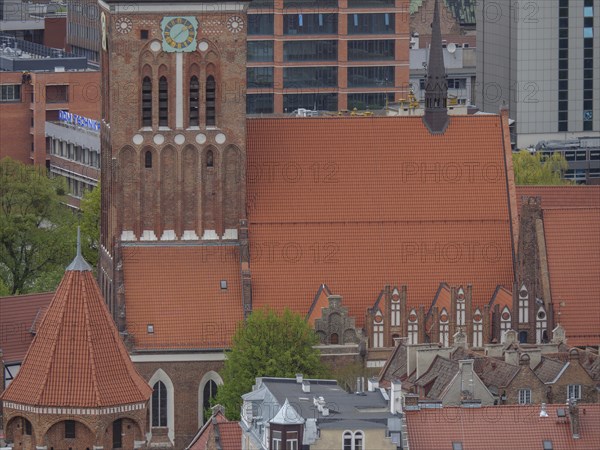Brick church tower against a backdrop of modern architecture and skyscrapers, Gdansk, Poland, Europe