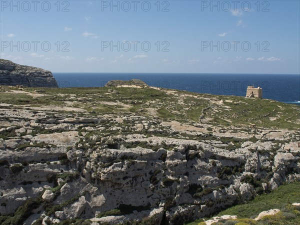 Rocky coastline with an old watchtower and sweeping views of the blue sea and sky, gozo, mediterranean, malta