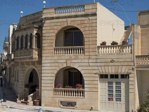 Two-storey sandstone building with balconies and flowers on a sunny day, Gozo, Mediterranean, Malta, Europe