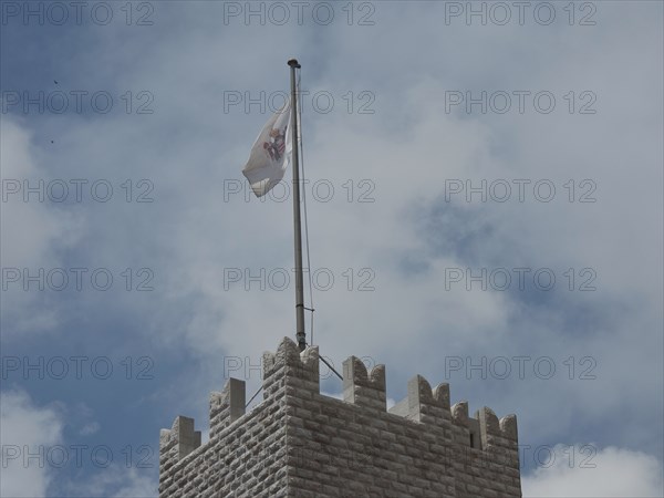 A medieval tower with a waving flag against a cloudy sky, monte carlo, monaco, france