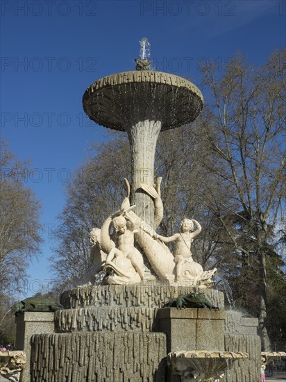 Large, artistic fountain with water jets and sculptures in the park under a blue sky, Madrid, Spain, Europe