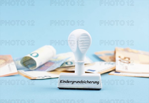 Basic child benefit stands in german language on the stamp, Euro banknotes in the background, new regulation for family in Germany