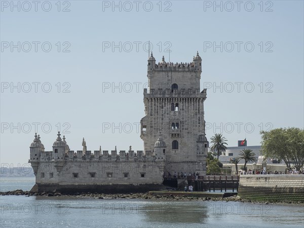Historic stone tower on the waterfront with palm trees and clear sky in the background, Lisbon, portugal