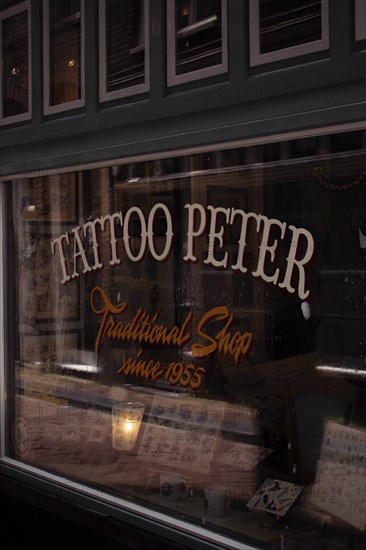 A traditional tattoo shop with a retro sign and nostalgic atmosphere, seen from the outside, Amsterdam, Netherlands