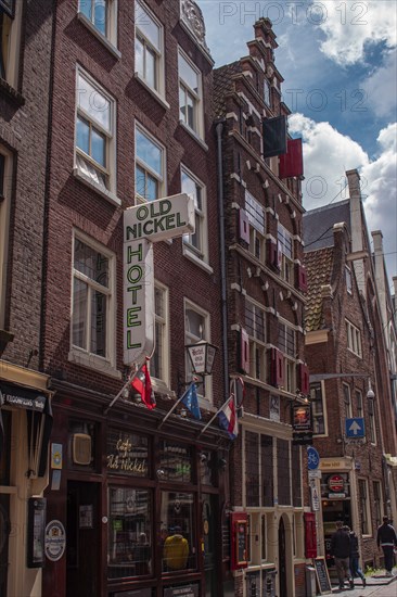 Historic hotel building in a city with brick façade with various flags, Amsterdam, Netherlands