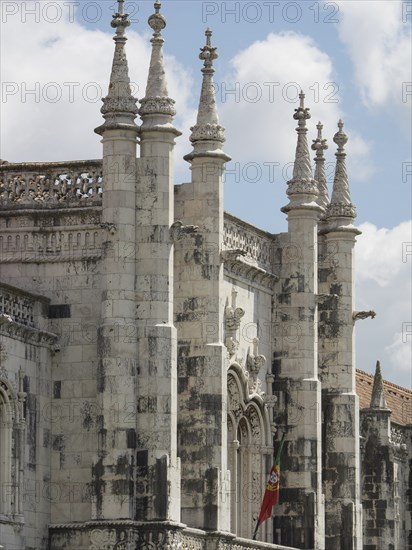 Detail of a gothic church façade with stone ornaments and towers under a cloudy sky, Lisbon, portugal