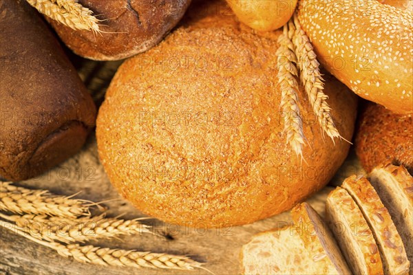 Homemade bread and wheat on the wooden table in autumn field