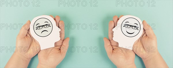 Holding a head with a sad and a happy face in the hands, mental health concept, positive and negative mindset, depression, support and evaluation symbol, emotion