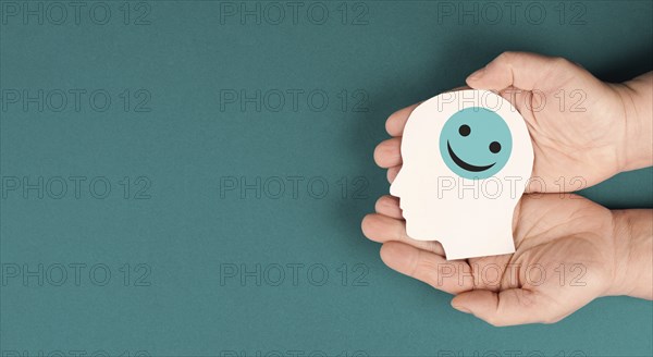 Holding a head with a smiling face in the hands, mental health concept, positive mindset, support and evaluation symbol