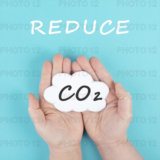 Hand holds cloud with the word CO 2, reduce carbon dioxide emission, environmental issue, air pollution