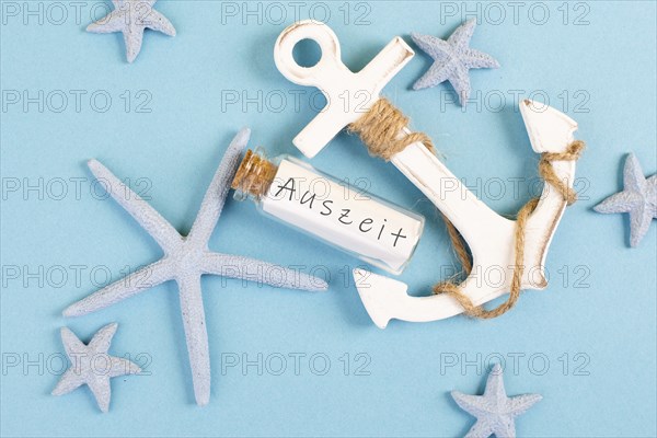 Time out is standing in german language on the glass bottle, blue colored summer and vacation background with anchor and sea stars, holiday, travel and tourism concept