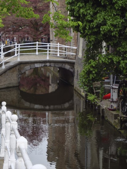 Romantic canal with a white bridge and building reflections in the calm water, Delft, Holland, Netherlands