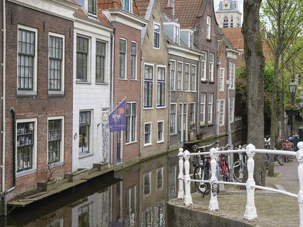 Row of old brick houses and bicycles standing along a canal in a historic town, Delft, Holland, Netherlands