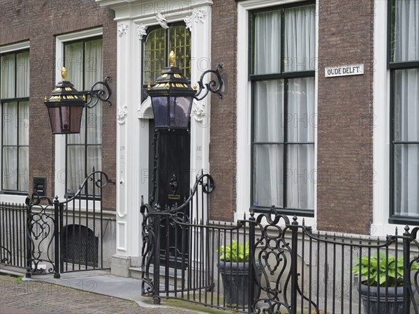 A stylish entrance to a historic city building with ornate lanterns and an iron gate, Delft, Holland, Netherlands