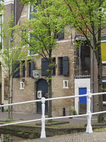 Old brick house with shutters and trees on the canal, Delft, Holland, Netherlands