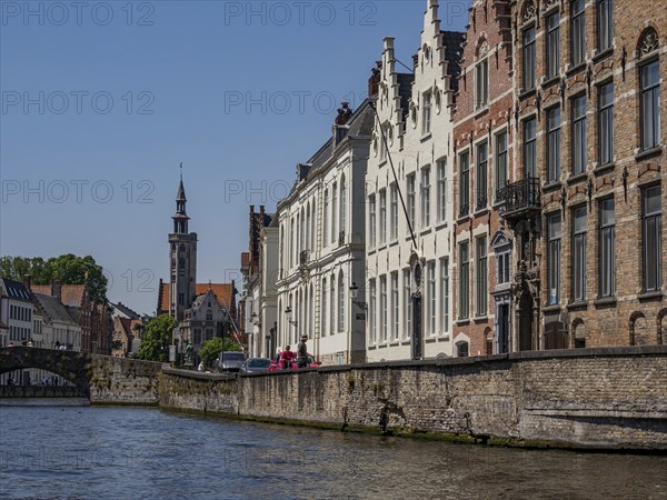 Historic buildings and a church tower along a canal with detailed architecture and blue sky, Bruges, Flanders, Belgium, Europe