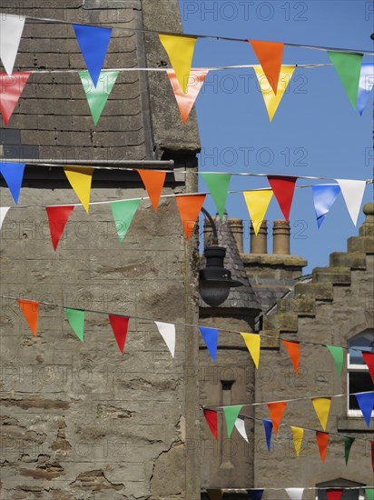 Colourful flags hang between traditional buildings under a bright sky, lerwick, shetlands, scotland, great britain