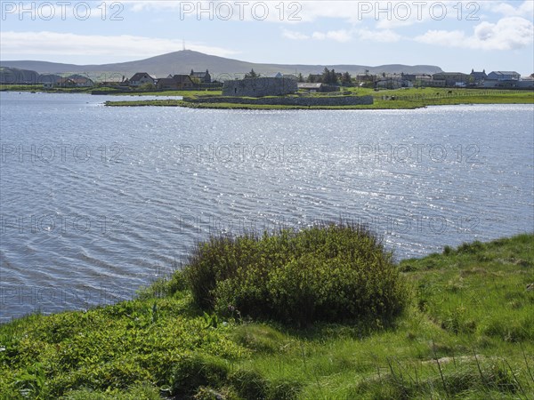 Picturesque landscape with hills and houses on the edge of a lake under a blue sky, lerwick, shetlands, scotland, Great Britain