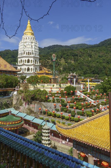 A pagoda in a temple complex with many lanterns and surrounding mountains under a blue sky, Pattaya, Thailand, Asia