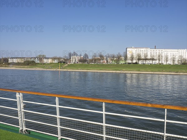 View from a ship's railing onto a river and apartment blocks in an urban environment, Cologne, North Rhine-Westphalia, Germany, Europe