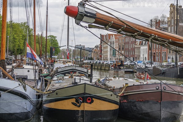 Several boats moored in the harbour, with a colourful background of buildings and flags, Dordrecht, holland, netherlands
