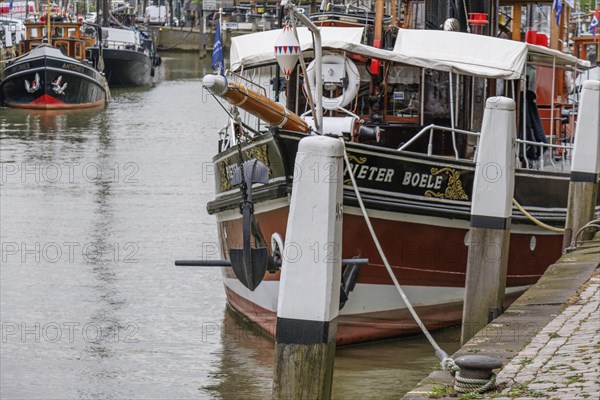 Detailed boat in the harbour, moored to pillars with anchor and white ropes in the foreground, Dordrecht, holland, netherlands