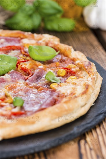 Fresh made Salami Pizza with basil on wooden background