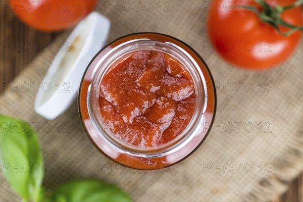Homemade Tomato Ketchup on an wooden table (selective focus) as detailed close-up shot
