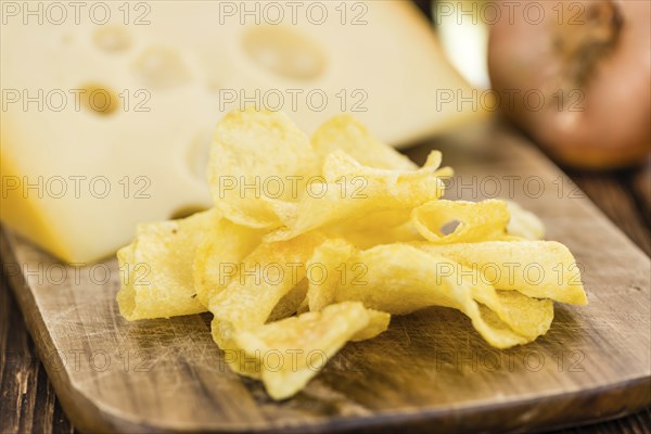 Cheese and Onion Potato Chips on an old wooden table as detailed close-up shot (selective focus)