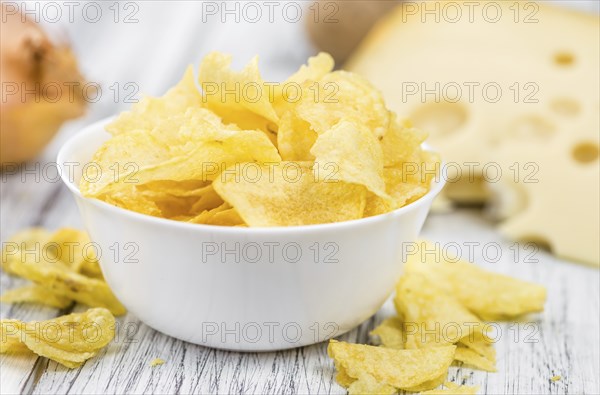 Cheese and Onion Potato Chips on a vintage background as detailed close-up shot (selective focus)