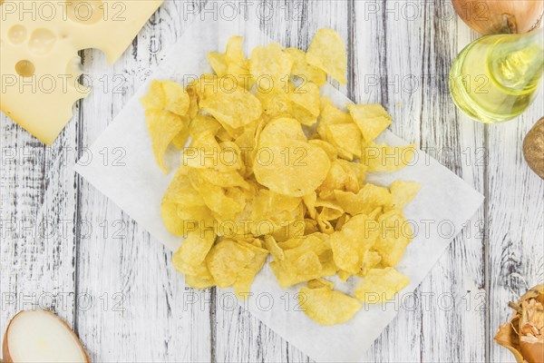 Cheese and Onion Potato Chips on an old wooden table as detailed close-up shot (selective focus)