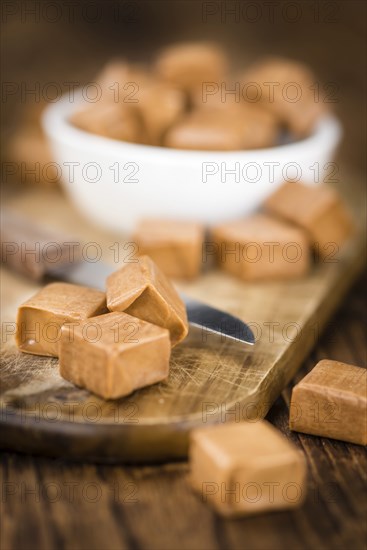 Caramel pieces as high detailed close-up shot on a vintage wooden table (selective focus)
