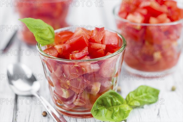 Tomatoes (diced) as high detailed close-up shot on a vintage wooden table (selective focus)