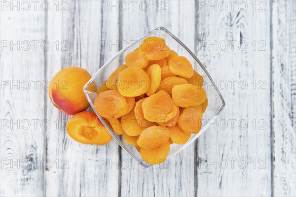 Dried Food (Apricots) on rustic wooden background (close-up shot)