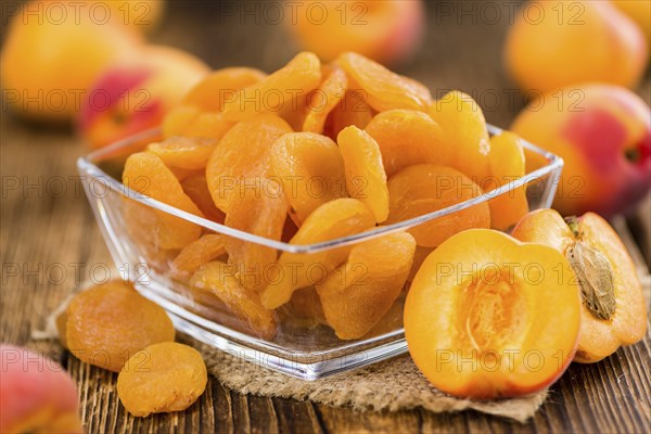 Dried Food (Apricots) on rustic wooden background (close-up shot)